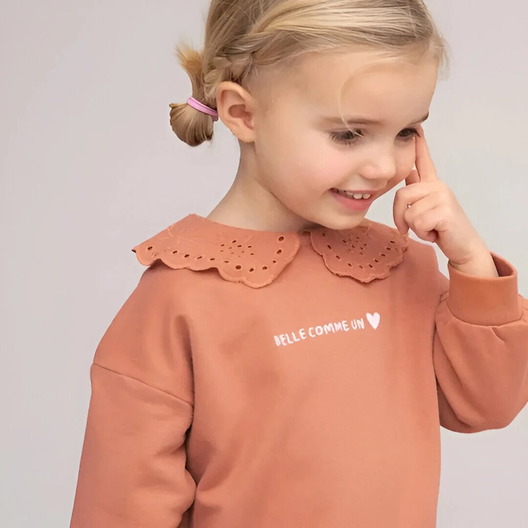 Bébé portant un pull représentant notre collection de vêtements pour fille 