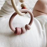 Bébé jouant avec l'anneau de dentition bébé silicone : Eden de couleur rose et beige